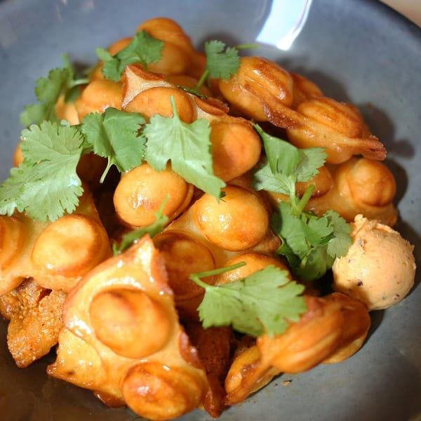 Old Thousand's golden brown bubble waffle dessert, garnished with fresh cilantro and a scoop of ice cream.